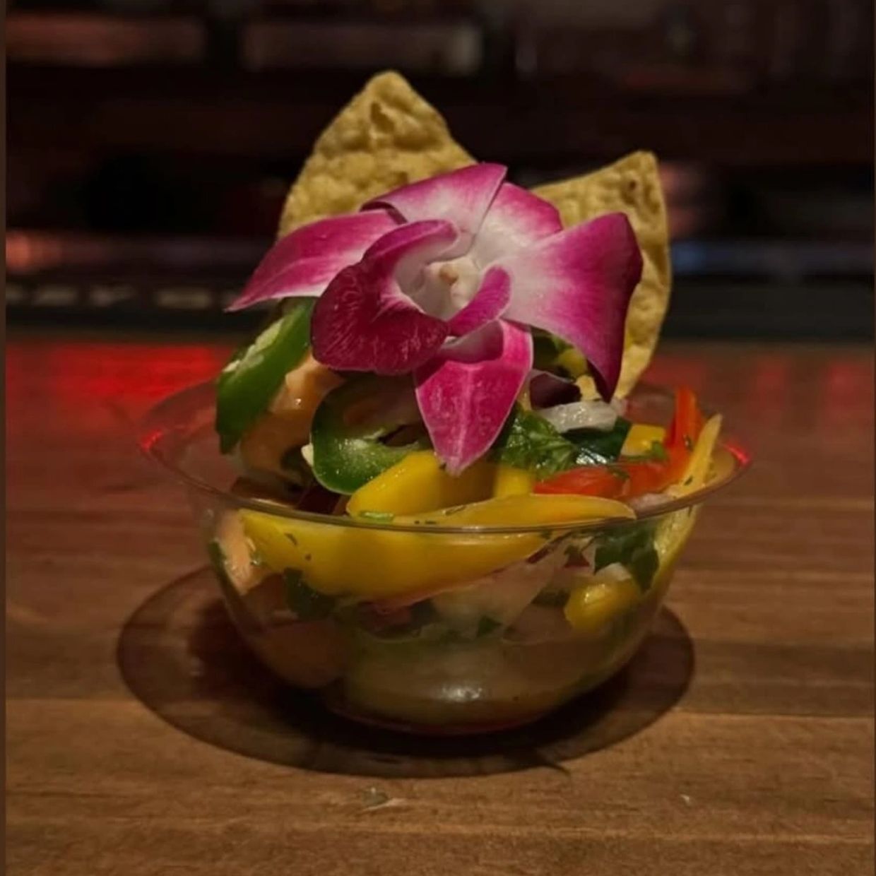 Colorful salad with a decorative pink flower and tortilla chips.