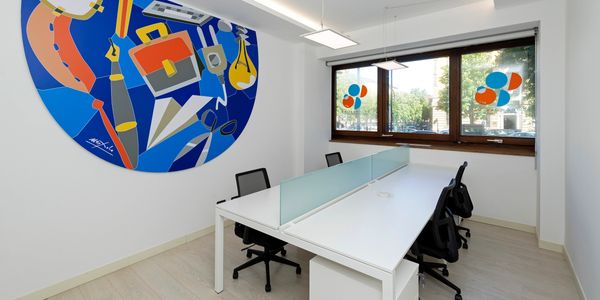 Modern office space with white desks, black chairs, and colorful abstract wall art.