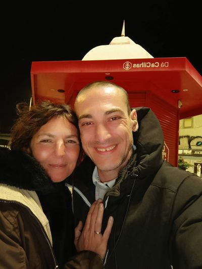 Smiling couple posing warmly together at night under a red DS Cecilhas structure.