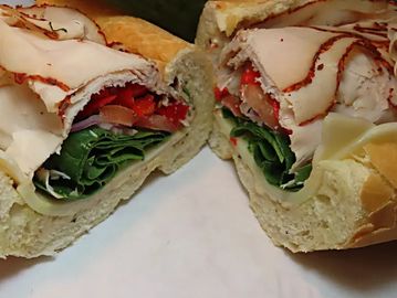 A sandwich with leafy vegetables and slices of meat