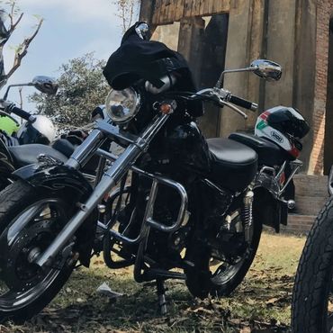 Two black motorcycles parked on grass with helmets resting on them.