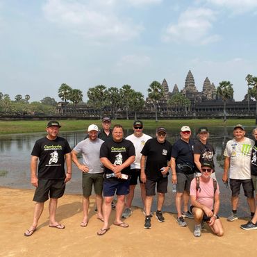 Group of tourists posing in front of Angkor Wat in Cambodia on a sunny day.