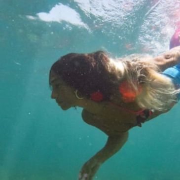 A woman Mermaid freediving in aquamarine water.