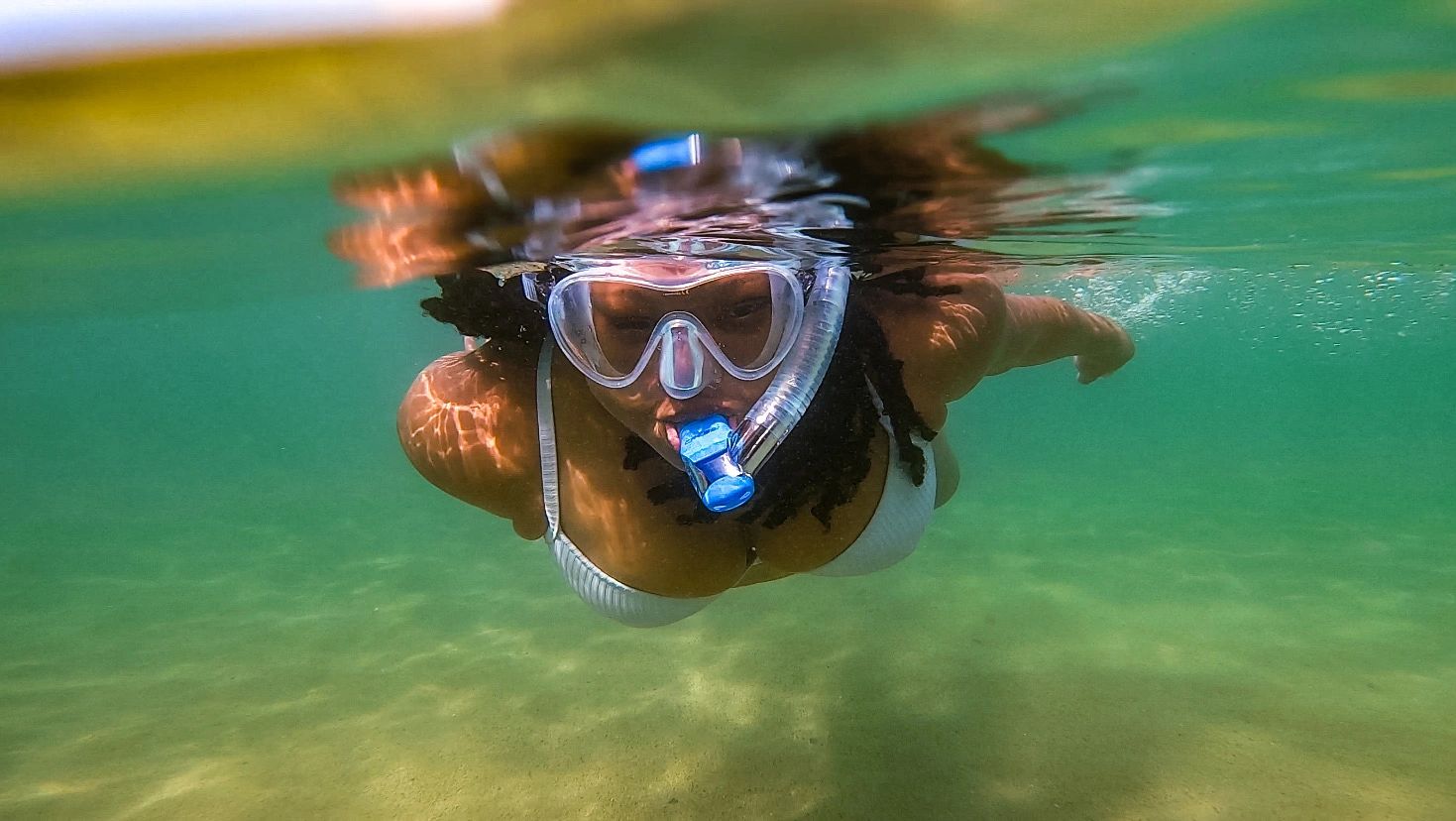 Snorkeling in a clear snorkel mask, a woman approached the camera in tropical water. 