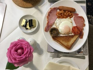 Traditional English breakfast with tea, served on a white tablecloth with a pink rose.