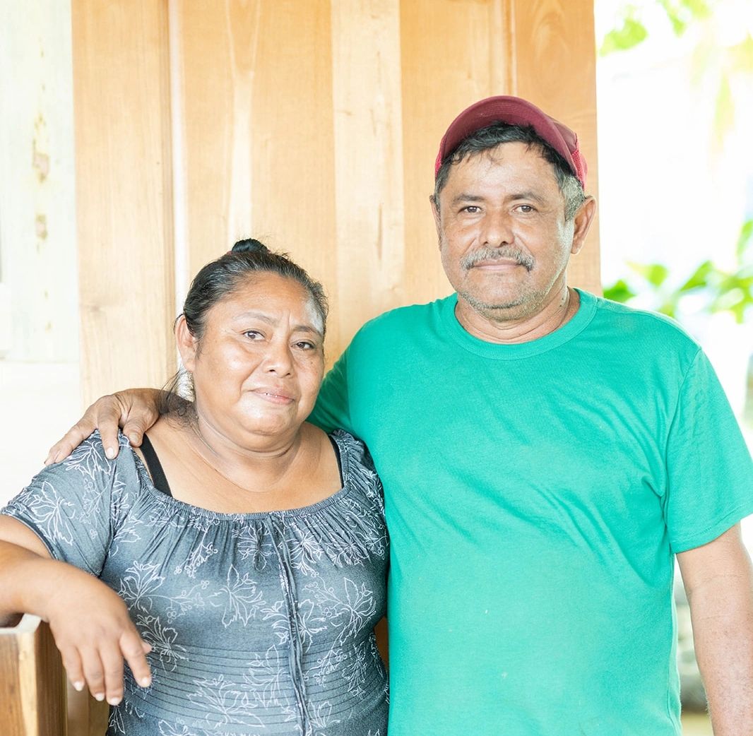 A couple stands close together, smiling gently at the camera.