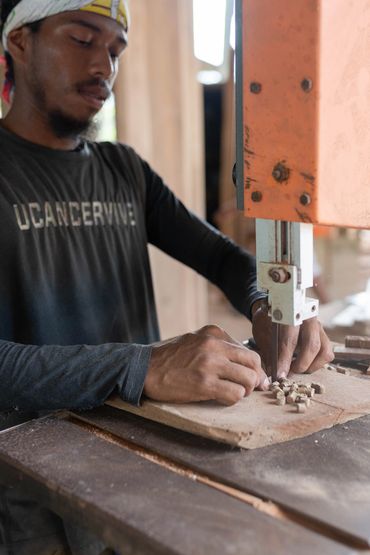 Man using a bandsaw to cut wood in a workshop.