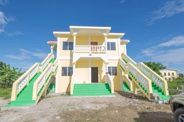 A cream-colored building with multiple green staircases under a clear blue sky.
