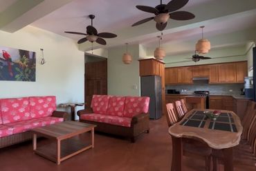Cozy living room and kitchen with pink floral sofas and wooden furniture.