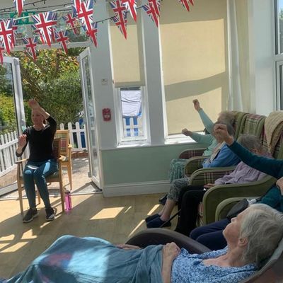 A group of elderly people performing chair yoga.