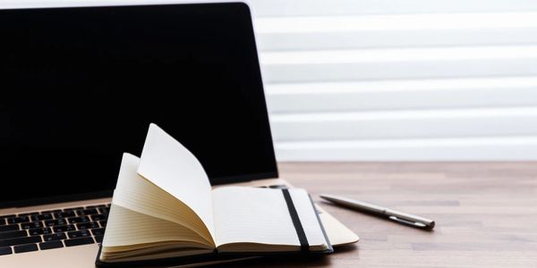 A laptop and notepad on a desk.