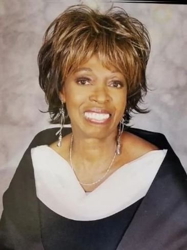 Smiling woman in formal attire with earrings.