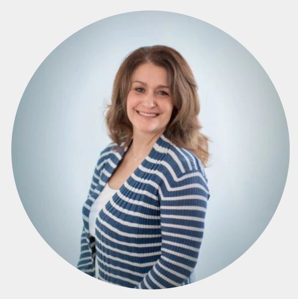 Smiling woman in a blue and white striped sweater against a soft blue background.