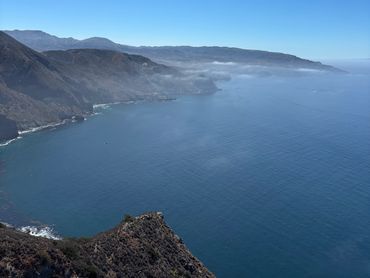 Coastal cliffs meeting the calm blue ocean under a clear sky.