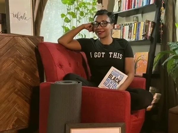 Founder sitting in chair with book and yoga mat