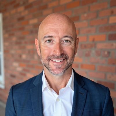 Smiling bald man in suit jacket and white shirt.