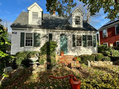 Charming white house with green shutters and a garden.