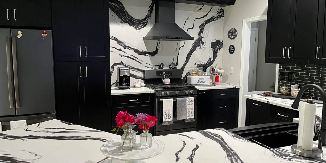 Modern kitchen with black cabinets and marble-patterned countertops and backsplash.