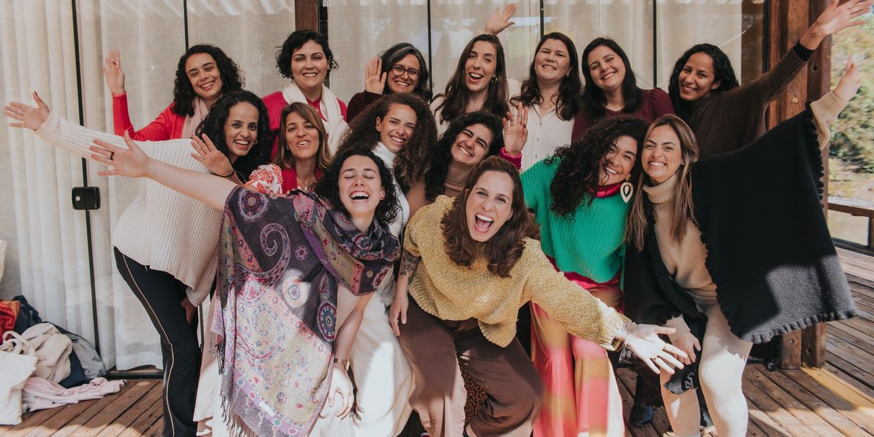 A joyful group of women smiling and posing together on a wooden deck.