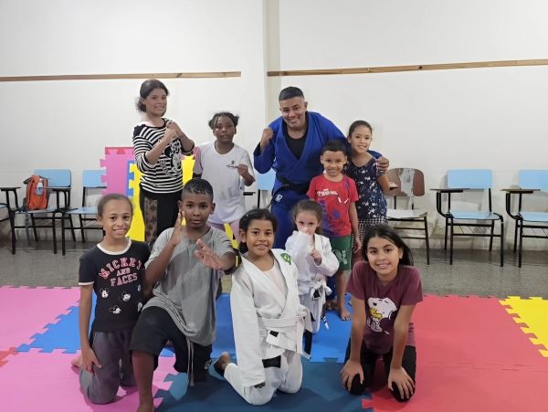 Grupo de crianças e um adulto em aula de judô.