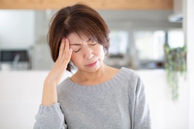 A woman with her eyes closed and a hand on her forehead