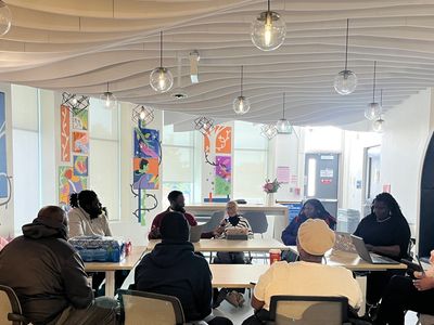 A group meeting in a modern, well-lit room with colorful wall art.