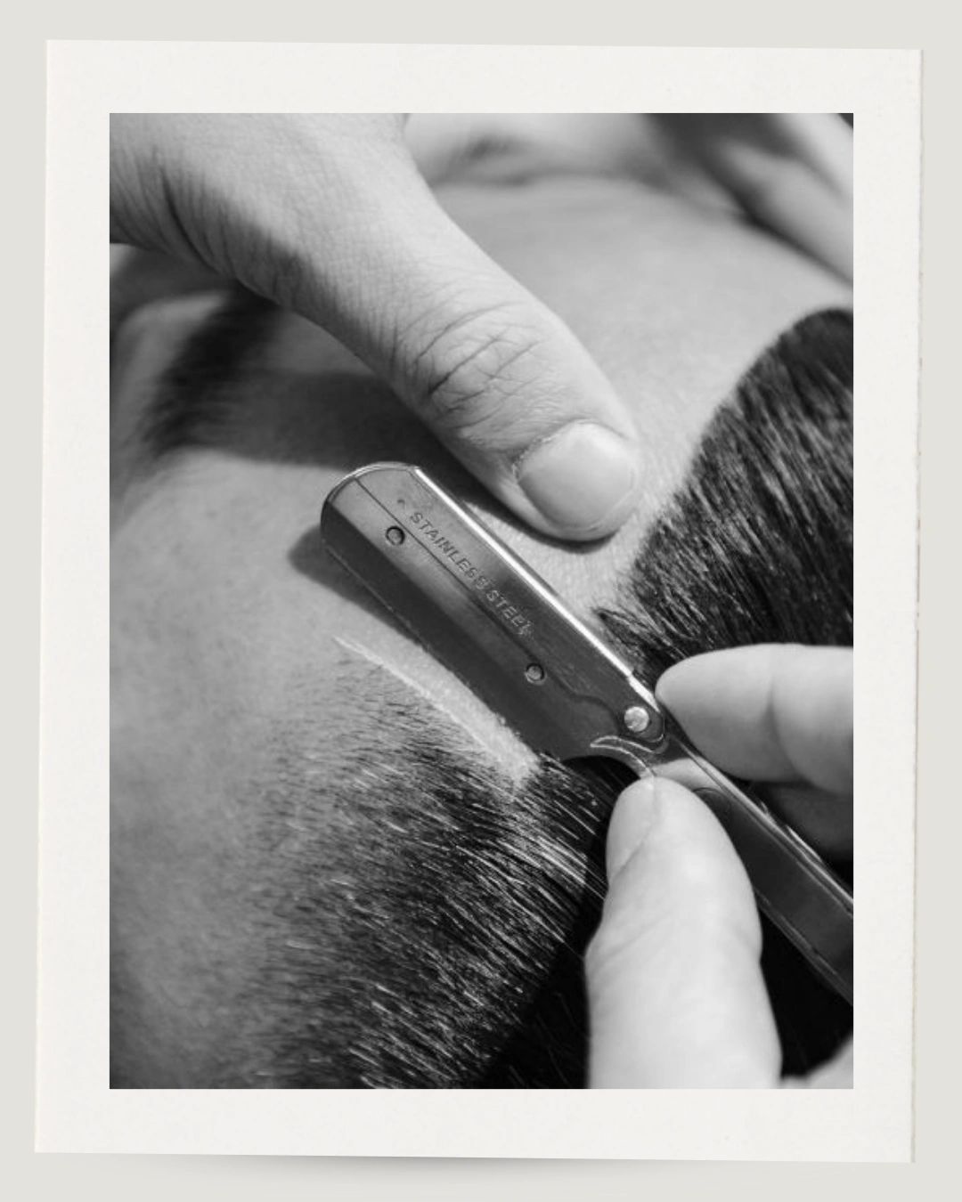 Close-up of a straight razor shaving a beard.
