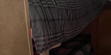 A cozy bed with a checkered blanket against a wall.