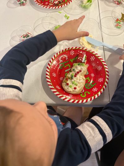 Child decorating a cookie on a festive Christmas plate.