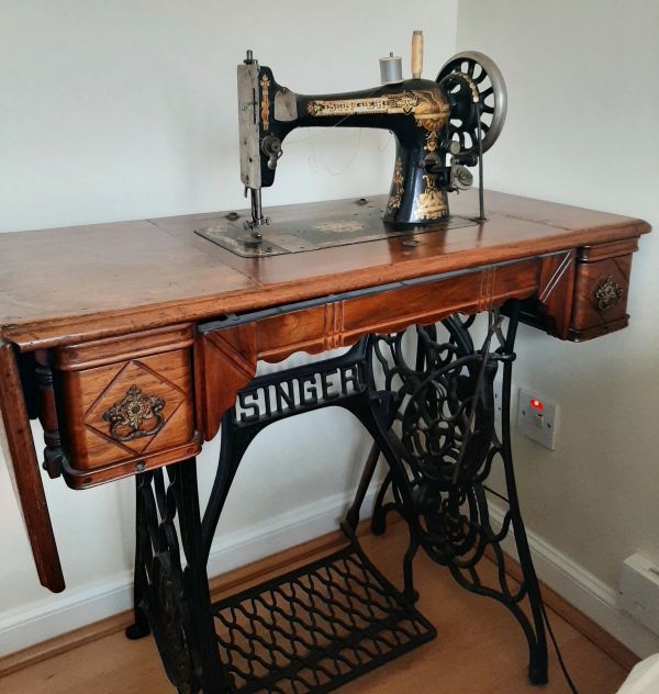 Vintage Singer sewing machine in wooden cabinet.