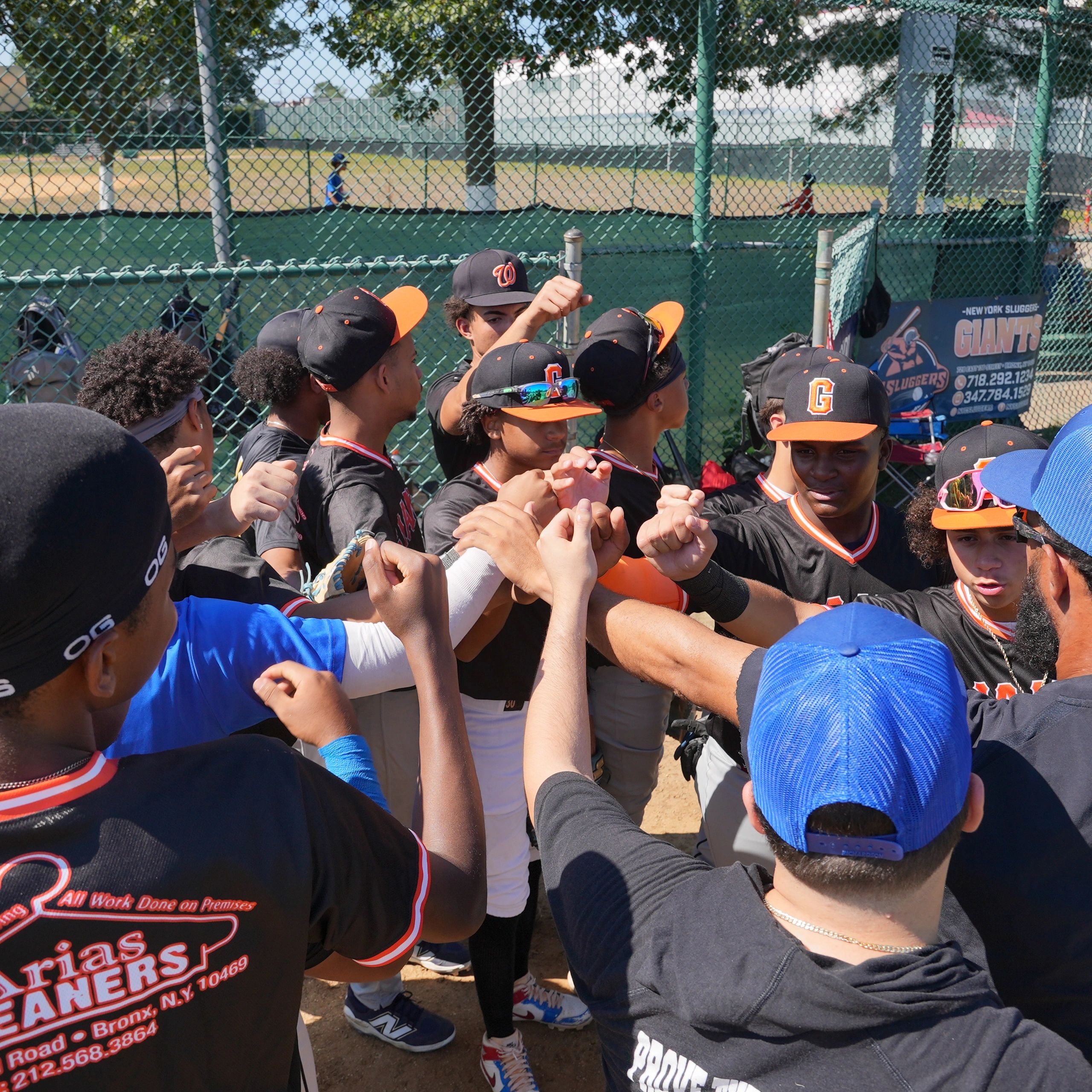 Youth baseball team group huddle with fists raised.