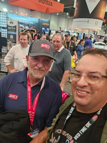 Two men smiling at a trade show or convention with branded lanyards.