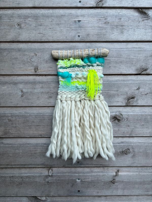 Vibrant Neon coloured weaving hung on a wooden background. Made from reclaimed & sustainable yarn.