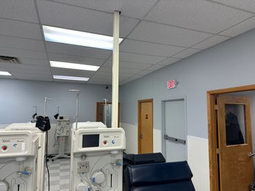 Medical dialysis machines in a clinic room with chairs and doors.
