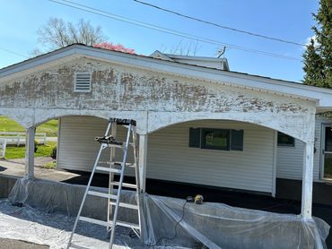 Ladder and tools set up for exterior house painting and repair work.