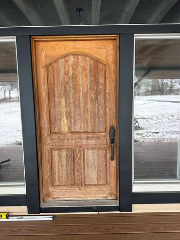 Wooden front door with glass panels on each side.