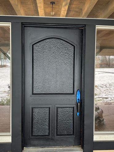 Black front door with textured glass panels and side windows.