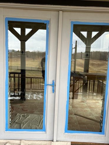 Newly painted double glass doors with blue painter's tape.