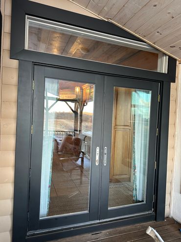Black framed glass double doors with reflections of a cozy interior and outdoor porch.