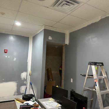 Office room with gray walls under renovation and a ladder.