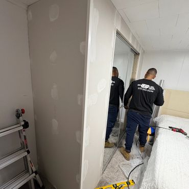 Man working on room renovation with drywall and tools around.