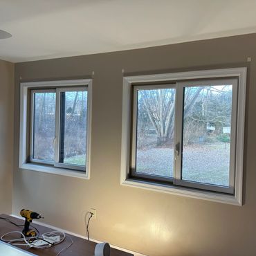 Room with beige walls, two sliding windows, and a table with tools and a lamp.