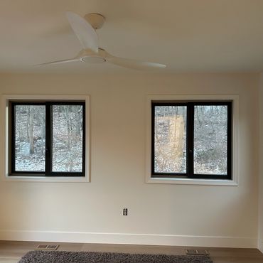 Empty room with three windows and a ceiling fan.