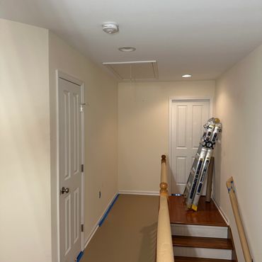 Hallway under renovation with painting supplies and a ladder.