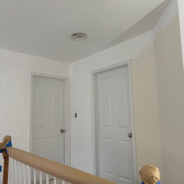 Interior hallway with two closed doors and painting supplies on the floor.