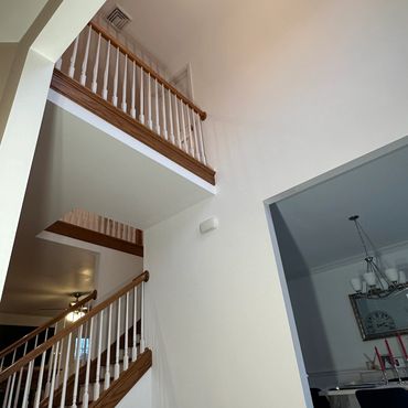Interior view of a staircase with wooden railings and a chandelier above.