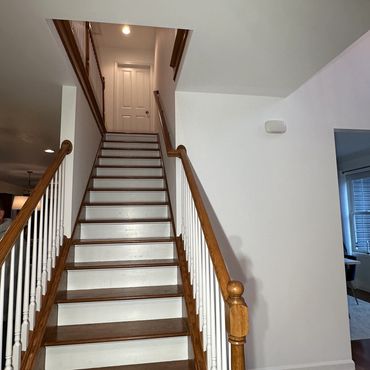 Wooden staircase with white risers leading to a closed white door at the top.