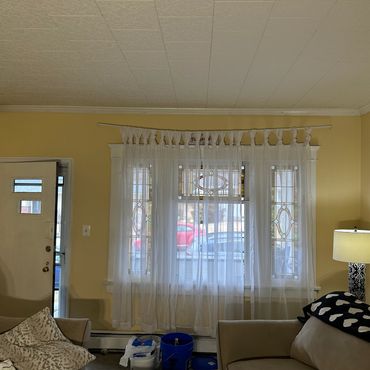 Cozy living room with yellow walls, sheer curtains, and a lit floor lamp beside a couch.