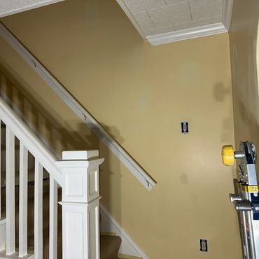 Interior staircase with white banister and beige walls under renovation.