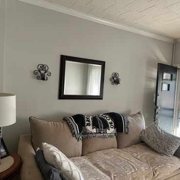 Cozy living room with beige couch, decorative pillows, and a patterned lamp beside a black door.